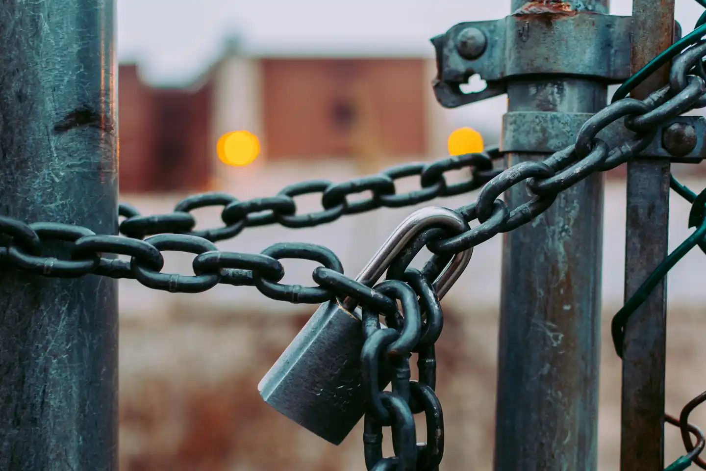 A padlock and chain holding a gate shut, photographed close up